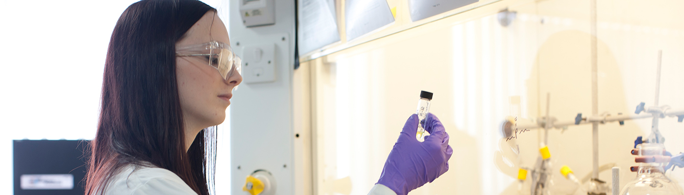 Researcher holding up test tube to inspect