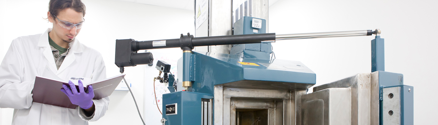 Researcher smiling with hands in radioactive material machine