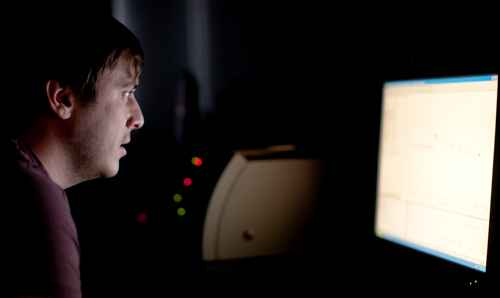Researcher in dark room with face illuminated by screen